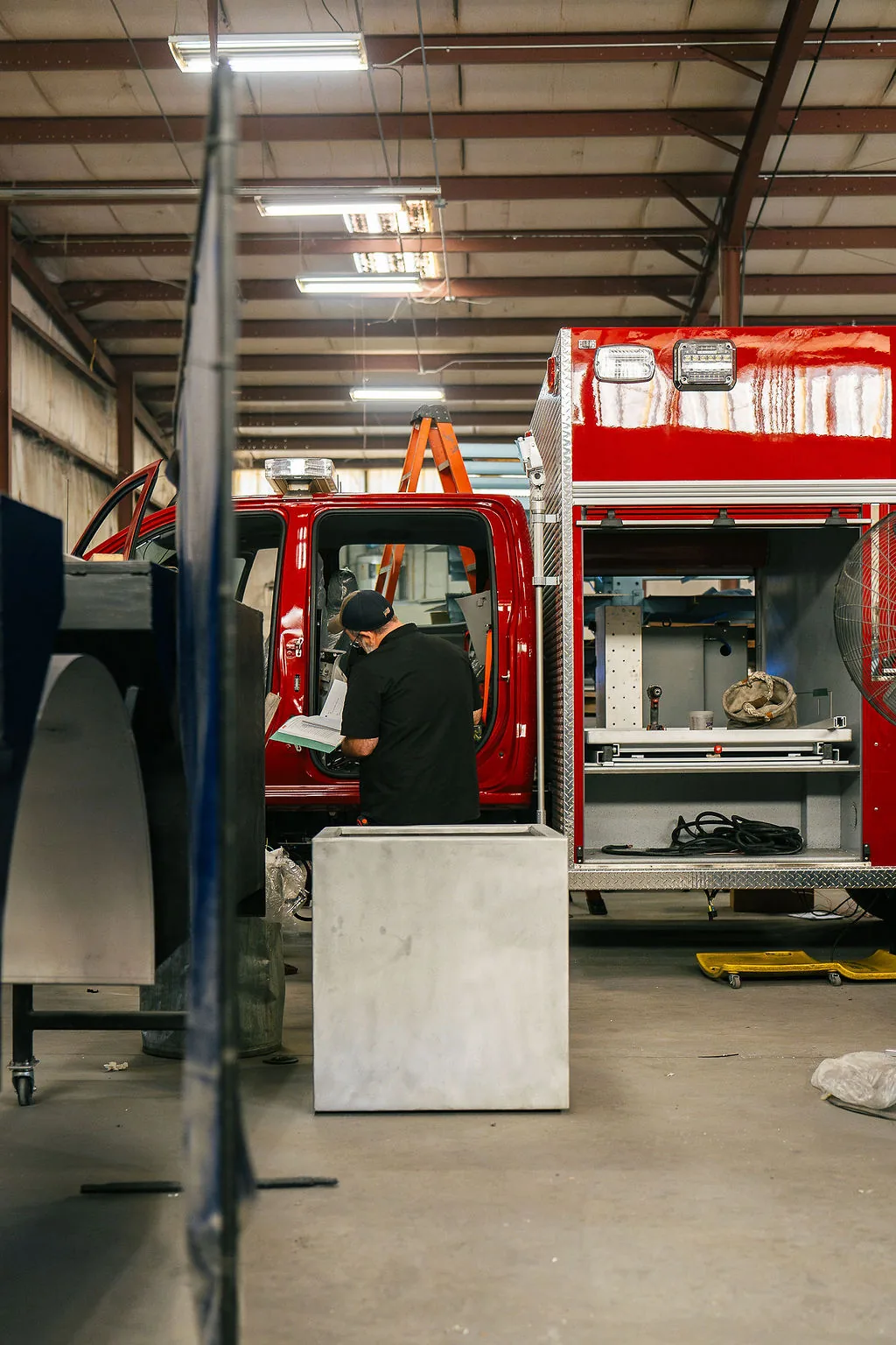 FES team member checking build documentation beside a fire apparatus body under construction