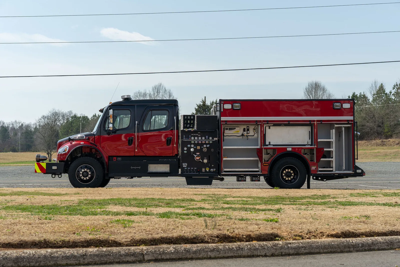 Side profile of a black over red FES pumper showing pump panel and open compartments